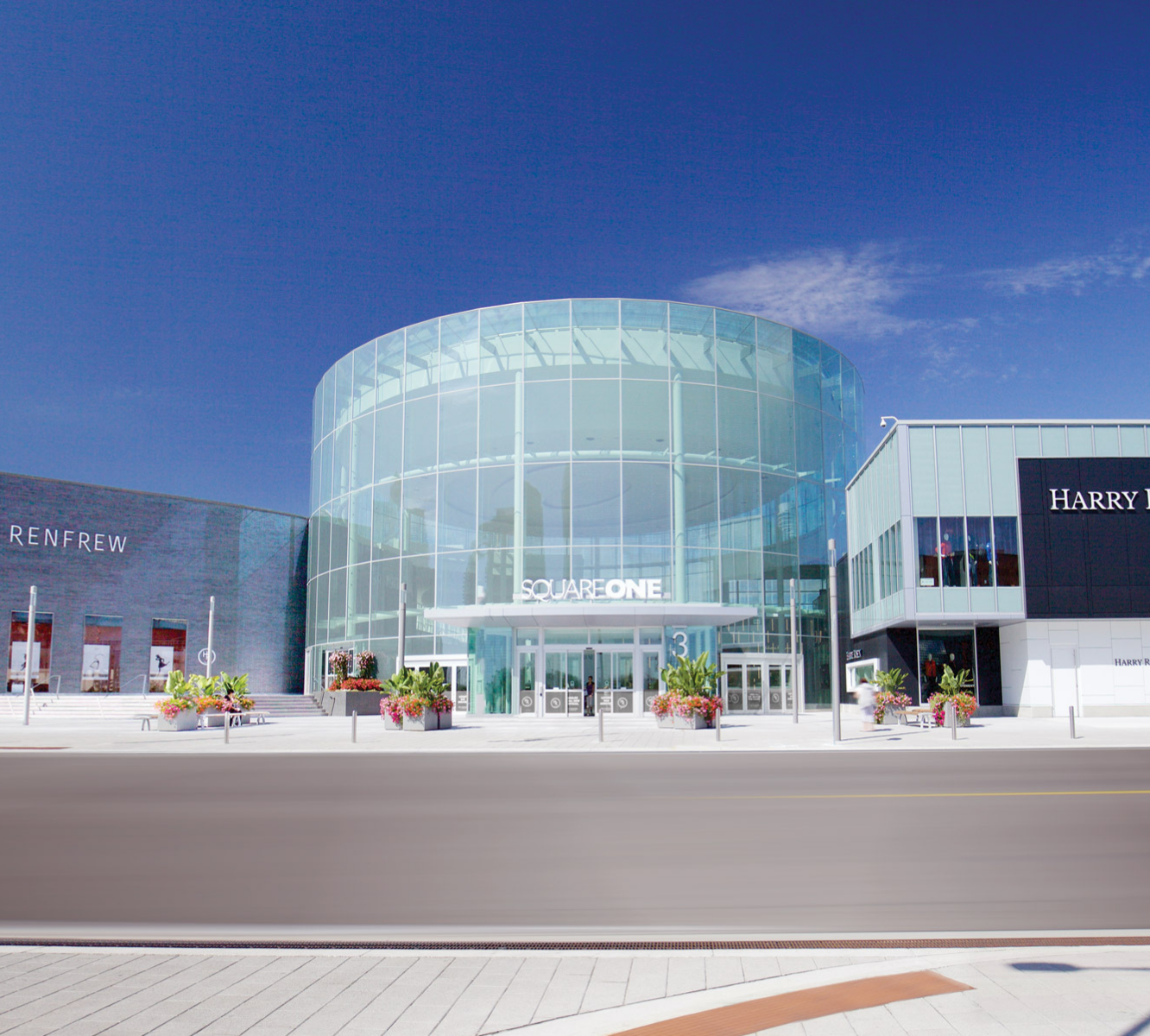 Exterior glass round entrance of Square One shopping centre summer time with bright blue sky.